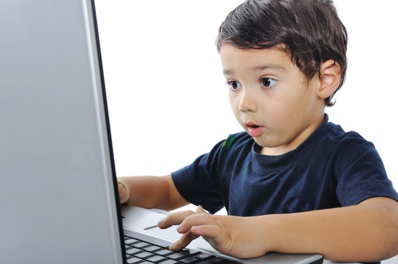 La imagen muestra a un niño sorprendido observando algo en un notebook