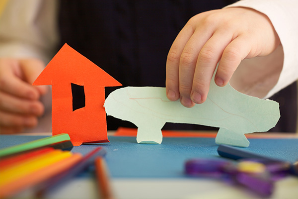 La imagen muestra la mano de un niño jugando con figuras de papel 