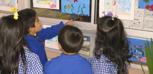 La imagen muestra un grupo de niños y niñas observando trabajos sobre el oceano