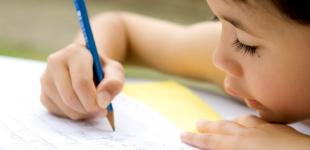 La imagen muestra a un niño escribiendo letras en un cuaderno