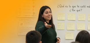 Fotografía de docente conversando con estudiantes en sala de clases.